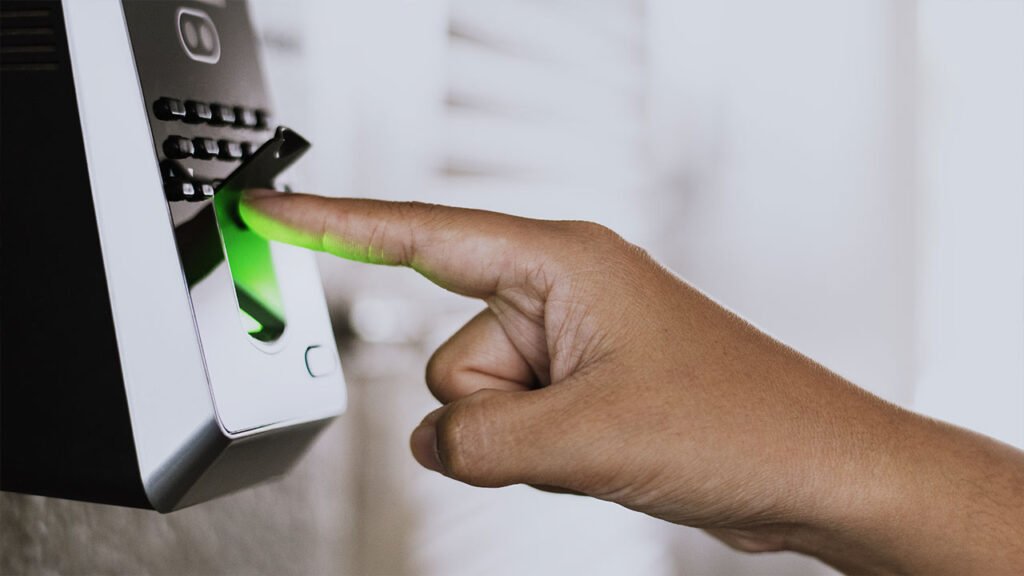 Pessoa pressionando o botão de uma fechadura eletrônica moderna em uma porta de apartamento, simbolizando o uso de tecnologia de ponta em residências de alto padrão.