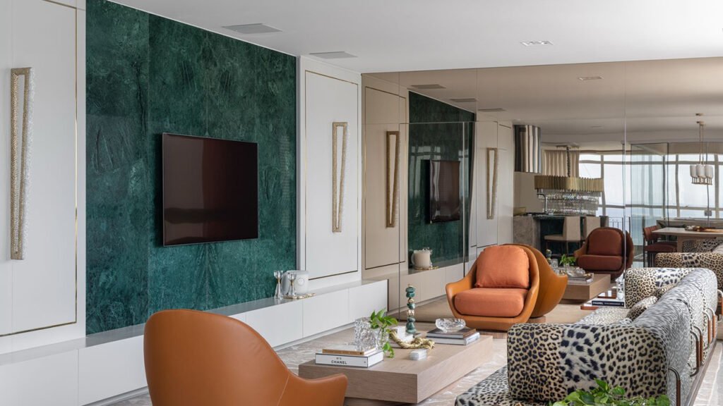 Sala sofisticada com poltronas em couro, sofá com estampa animal print e parede em verde profundo – composição ousada nas tendências de decoração para o inverno 2025.